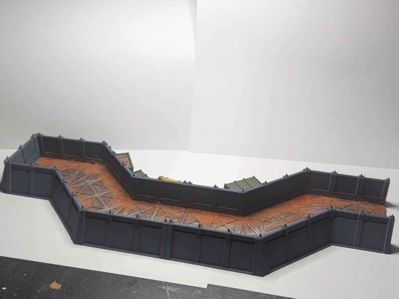 Modular printed trench sections with dark iron corrugated walls and rust-stained muddy floors, assembled in a zigzag pattern